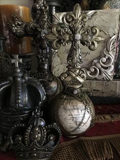 an ornate cross is sitting on top of some other decorative items in front of a candle holder