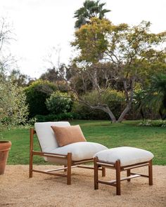 an outdoor lounge chair and ottoman in the middle of a field with trees behind it