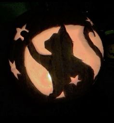 a carved pumpkin with a silhouette of a cat in the center and stars on it