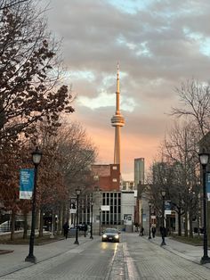 a car is driving down the street in front of a tall building with a spire on top