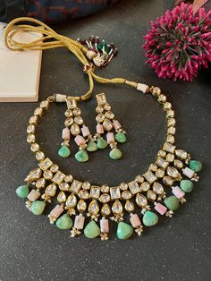 Perfect for destination weddings! You will definitely fall in love with the beautiful Kundan set. The gorgeous necklace is beautifully handcrafted by our skilled Indian craftsmen in the finest quality Kundan stones. The real green chrysoprase and pink Opal hangings add perfect glamour to the stunning necklace set. Material: Brass, Kundan Stones, and gold polish, chrysoprase and pink Opal stones  The pretty earrings add to the beauty of this stunning piece. Dimensions Weight of Necklace is 108 g. Necklace comes with adjustable Dori. Weight of Earrings is 28 g per pair. Length of Earrings: 6.5 cms, push back closure. Width of Earrings: 3 cms. Green Kundan Gemstone Jewelry Set, Kundan Jewelry Set With Green Gemstones, Turquoise Natural Stones Wedding Jewelry, Handmade Green Bridal Necklace For Wedding, Turquoise Wedding Jewelry With Natural Stones, Green Gemstone Jewelry Sets For Celebration, Handmade Green Emerald Necklace For Wedding, Green Gemstone Jewelry For Celebration, Turquoise Natural Stone Necklaces For Weddings