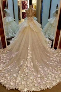 a wedding dress with flowers on it in front of a mirror and mannequins