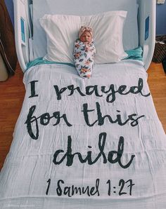 a baby laying on top of a bed under a blanket that says i raised for this child