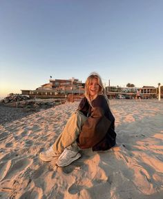 a woman sitting on top of a sandy beach