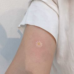 a person with a small white flower tattoo on their arm