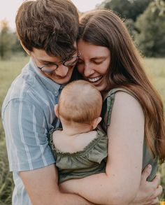 a man and woman holding a baby in their arms