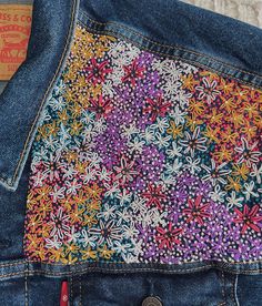 the back pocket of a pair of jeans with colorful flowers on it and a tag