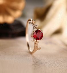 a close up of a ring with a red stone in the shape of an antelope