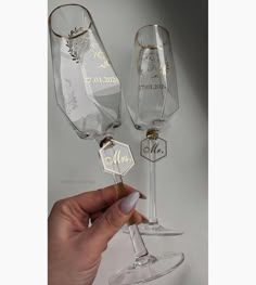 two wine glasses with their names engraved on the bottom and one is holding a small piece of paper