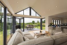 a living room filled with furniture next to an open kitchen and dining room area on top of a field