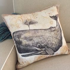 a pillow with a whale on it is sitting on a couch next to a tree