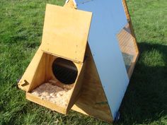 a cat house made out of wood and metal with a door open on the grass