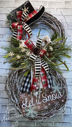 a christmas wreath hanging on the side of a brick wall next to a sign that says let it snow