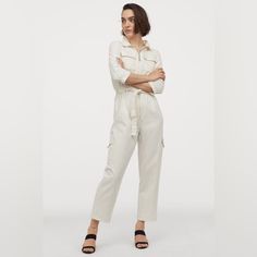 Jumpsuit In Cotton Denim With A Soft, Brushed Finish. Collar, Concealed Zipper At Front, And Yoke At Back. 3/4-Length Sleeves, Chest Pockets With Flap, And Tapered Waist With Attached Tie Belt At Front. Tapered Legs And Leg Pockets With Flap. Color Is Listed As White More Of A Cream/Off White Color. Summer Cotton Denim Jumpsuit For Work, Trendy Cotton Denim Jumpsuit For Work, High-waisted Cotton Denim Jumpsuit For Work, Chic Cotton Denim Jumpsuit For Work, Spring Workwear Overalls In Relaxed Fit, Cotton Denim Jumpsuit For Work, Trendy Spring Overalls For Workwear, High Waist Jumpsuits And Rompers For Spring Workwear, Spring Workwear Overalls