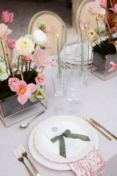 the table is set with pink and white flowers in vases, silverware, and napkins