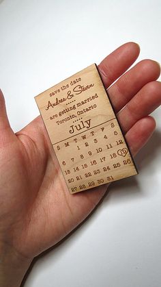 a hand holding a wooden ticket with the date and time printed on it's side