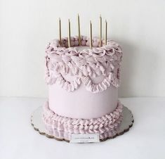 there is a pink cake with gold candles on it