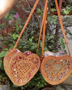 two heart shaped purses are hanging from a planter with flowers in the background