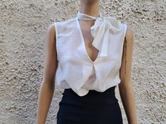 This ivory white sleeveless blouse is essential to any well-edited wardrobe. Laid back yet chic, it's crafted in 100% pure silk with a pleat relaxed shape and flattering / boat neckline. Perfect for event, work or off-duty dressing it will take you through the new season and beyond. * Measurements: Size S  Bust :50 cm ( 20'' in)- laying flat measured from one armpit to the other. Hips :54 ( 21'' in) Long : 56 cm ( 22'' in)- length measurement is taken from top of the front shoulder to hem. Size Elegant V-neck Blouse For Summer, Elegant V-neck Top With Bow, Classic V-neck Party Top, Elegant Spring Tie Neck Blouse, Elegant Tie Neck Blouse For Daywear, Elegant Fitted Blouse With Bow, Fitted Elegant Blouse With Bow, White Tie Neck Blouse For Summer, Elegant Evening Top With Bow