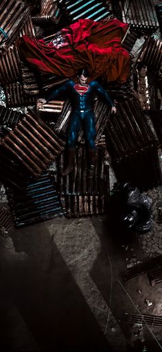 a man is laying on top of a pile of wooden slats in the dark