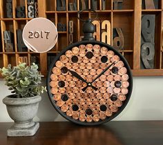 a clock made out of wine corks sitting on a table next to a potted plant