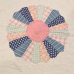 a patchwork quilt with blue, pink and white fabric in the shape of a flower