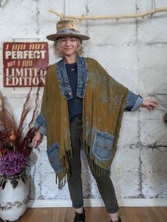 a woman standing in front of a wall wearing a hat