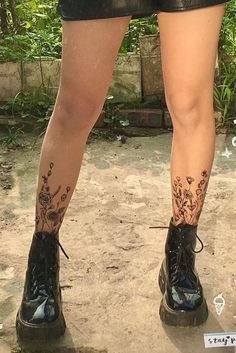 the legs and ankles of a woman with tattoos on her leg, wearing black shorts