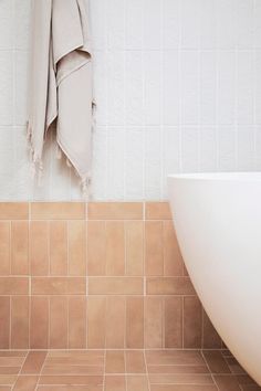 a white bath tub sitting next to a tiled wall