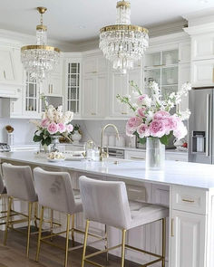 a kitchen with white cabinets and chandeliers