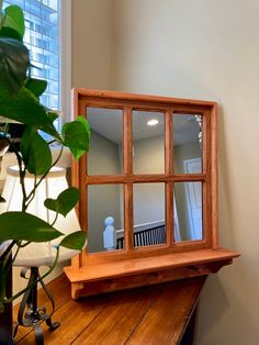 a mirror sitting on top of a wooden table next to a potted green plant