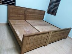 a bed with wooden headboard and foot board in a blue walled room, next to a window