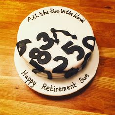 a white cake with black numbers on it sitting on top of a wooden table in front of a wood floor