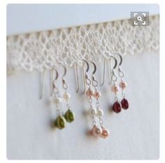 five different colored beads hanging from a white lace