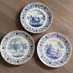 three blue and white plates sitting on top of a wooden table next to each other