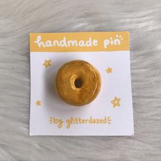 a small donut is sitting on top of a white piece of paper that says handmade pin