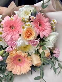 a bouquet of pink and white flowers sitting on top of a cloth covered tablecloth