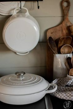 a white casserole sitting on top of a counter next to wooden spoons