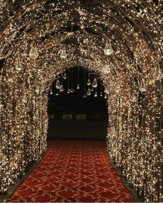 a red carpet with lights on it in the middle of a tunnel that is lit up