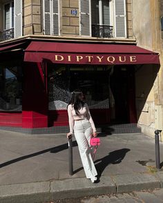 a woman standing on the sidewalk in front of a store