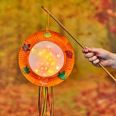 a hand holding a paper plate with lights on it and a stick in the air