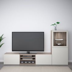 a flat screen tv sitting on top of a wooden entertainment center next to a potted plant