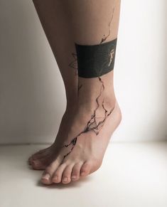 a woman's bare foot with a black and white tattoo on her left leg