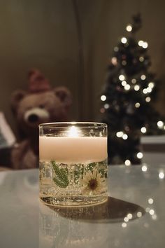 a lit candle sitting on top of a table next to a teddy bear and christmas tree