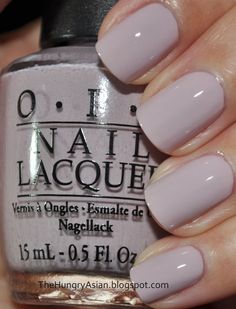 a woman's hand holding a bottle of opi nail polish in grey and white