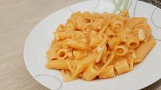 a white plate topped with macaroni and cheese on top of a wooden table