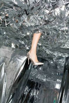 a woman's high heeled shoe sticking out of an aluminum foil covered box