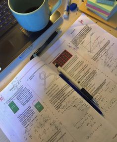 an open notebook sitting on top of a table next to a cup of coffee and laptop computer