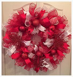 a red and white christmas wreath hanging on a door