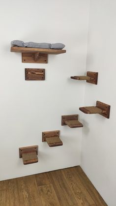 several wooden shelves with pillows on them in a white walled room and wood flooring